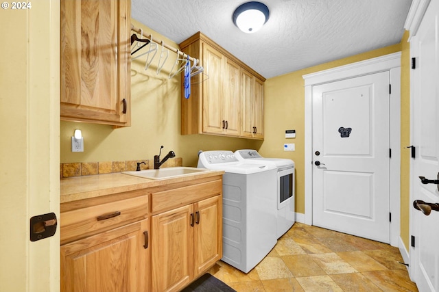 washroom with sink, washing machine and dryer, cabinets, and a textured ceiling