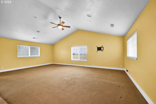 carpeted spare room with vaulted ceiling, ceiling fan, and a textured ceiling