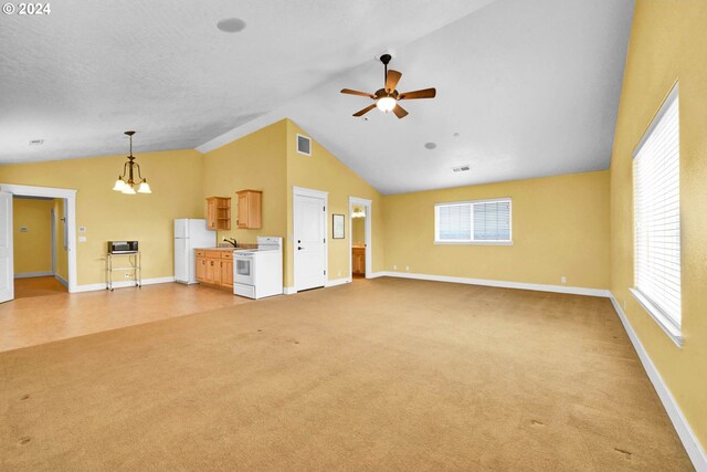 unfurnished living room featuring vaulted ceiling, ceiling fan with notable chandelier, light carpet, and a wealth of natural light