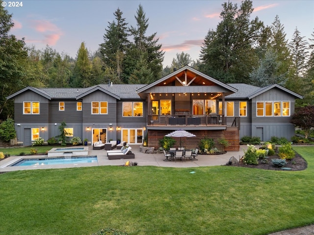 back house at dusk featuring a patio, a pool with hot tub, an outdoor living space, and a yard