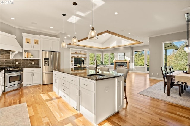 kitchen featuring appliances with stainless steel finishes, a center island with sink, white cabinets, sink, and dark stone countertops