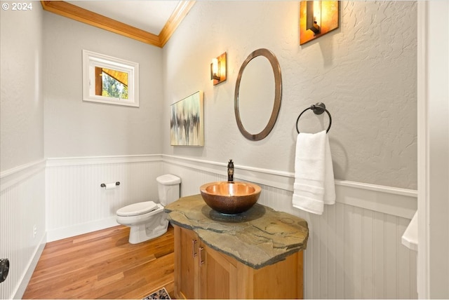 bathroom with toilet, ornamental molding, vanity, and wood-type flooring