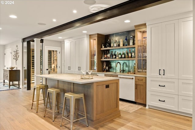 bar featuring white cabinets, light hardwood / wood-style flooring, and dishwasher