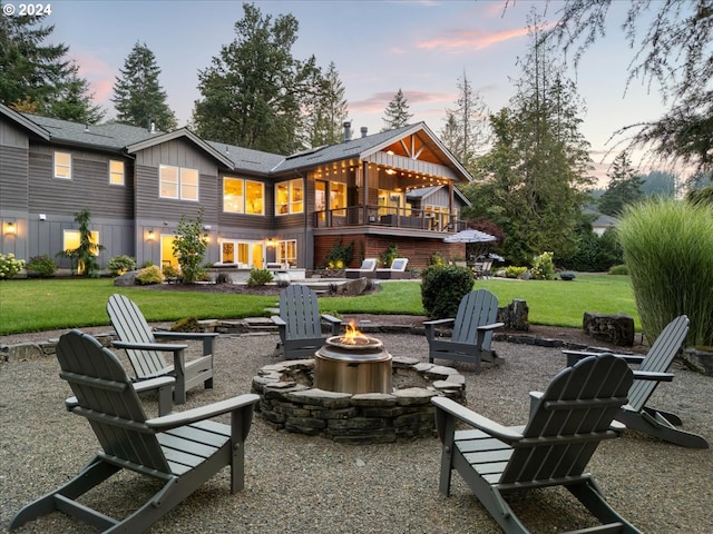 back house at dusk with a patio area, a lawn, and an outdoor fire pit