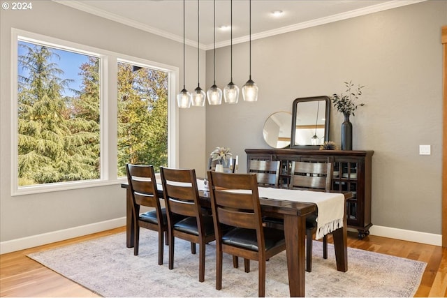 dining area with ornamental molding and light hardwood / wood-style flooring