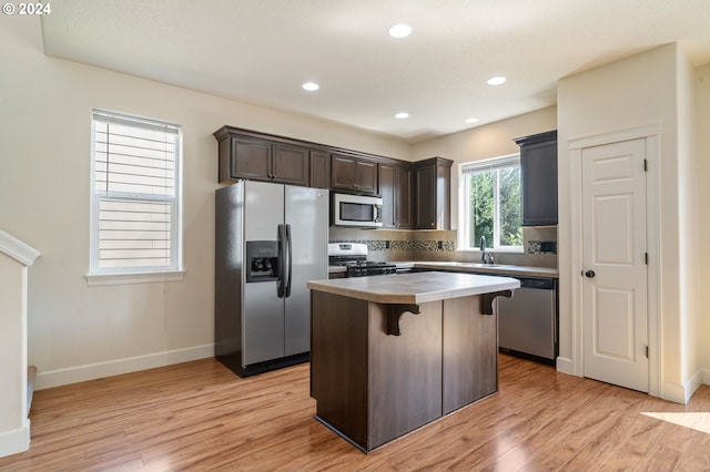 kitchen with light hardwood / wood-style floors, sink, stainless steel appliances, a center island, and dark brown cabinets