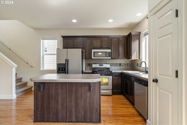 kitchen with stainless steel appliances, light hardwood / wood-style floors, a center island, and dark brown cabinets