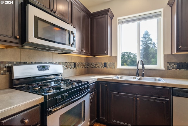 kitchen with appliances with stainless steel finishes, a wealth of natural light, sink, and dark brown cabinetry