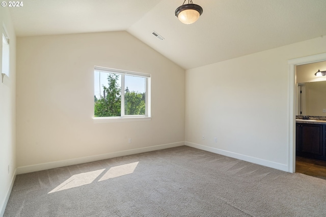 unfurnished bedroom featuring carpet flooring, vaulted ceiling, and ensuite bathroom