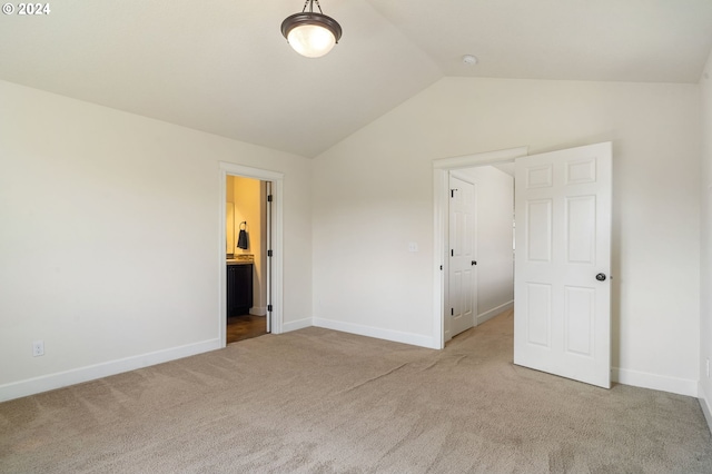 unfurnished bedroom with vaulted ceiling, connected bathroom, and light carpet