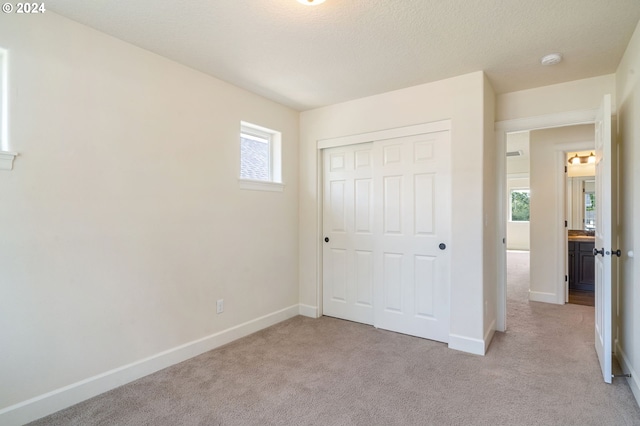 unfurnished bedroom with a closet and light colored carpet