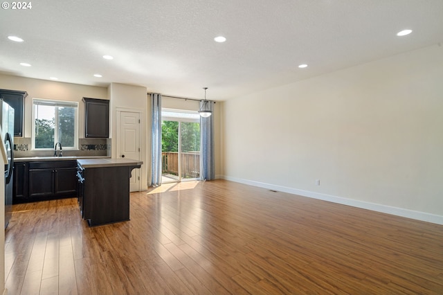 kitchen with light hardwood / wood-style floors, plenty of natural light, a kitchen island, and decorative light fixtures