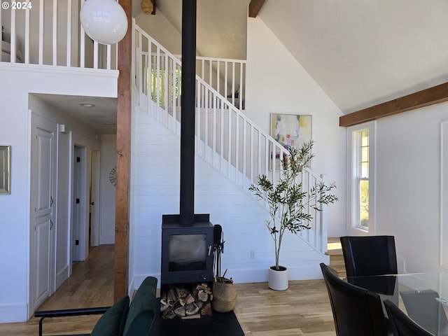 interior space with hardwood / wood-style flooring, high vaulted ceiling, and a wood stove