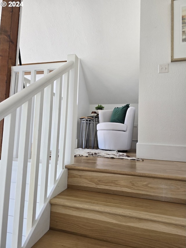 stairway with hardwood / wood-style flooring and lofted ceiling