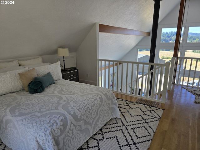 bedroom featuring hardwood / wood-style flooring, multiple windows, vaulted ceiling, and a textured ceiling