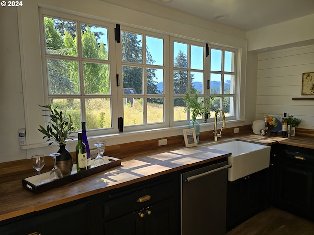 kitchen with sink, stainless steel dishwasher, wooden counters, and wood walls