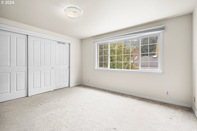 unfurnished bedroom with a closet and light colored carpet