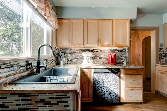 kitchen featuring black dishwasher, wood-type flooring, sink, light brown cabinetry, and tasteful backsplash