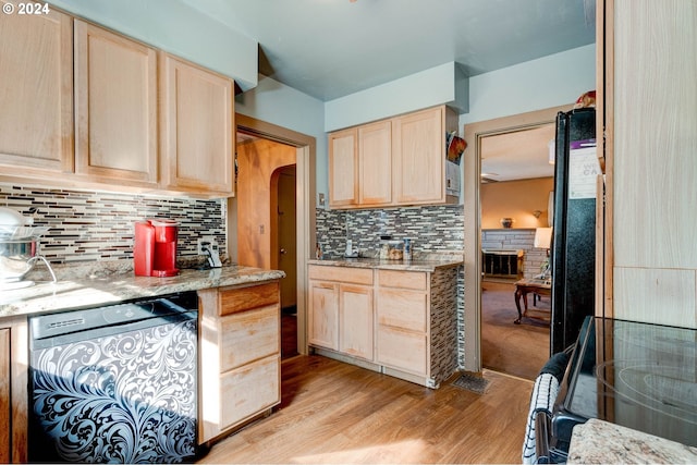 kitchen featuring black dishwasher, light stone countertops, and light wood-type flooring