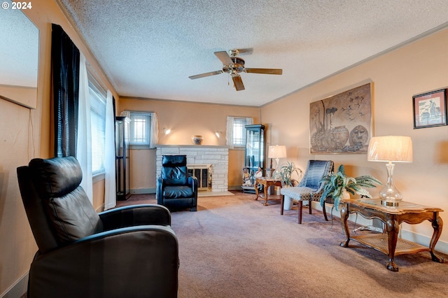 carpeted living room featuring a stone fireplace, a textured ceiling, and ceiling fan