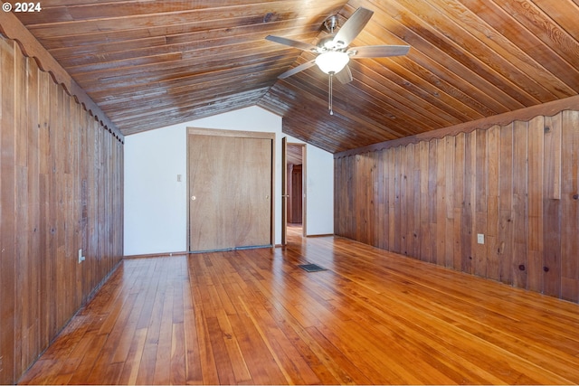 bonus room with wood walls, lofted ceiling, wood ceiling, hardwood / wood-style flooring, and ceiling fan