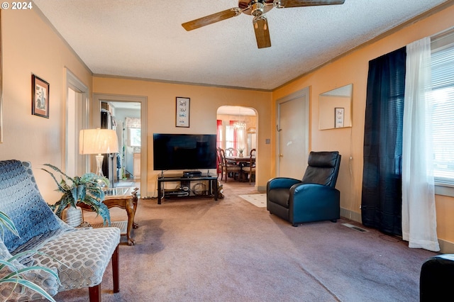 living room featuring carpet, ceiling fan, crown molding, and a textured ceiling