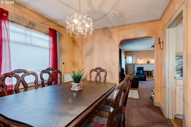 4310 NE 33rd Ave, Portland, OR 97211 - dining room with a textured ceiling, arched walkways, carpet flooring, a chandelier, and a stone fireplace