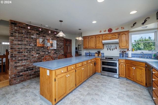 kitchen with sink, kitchen peninsula, brick wall, pendant lighting, and appliances with stainless steel finishes