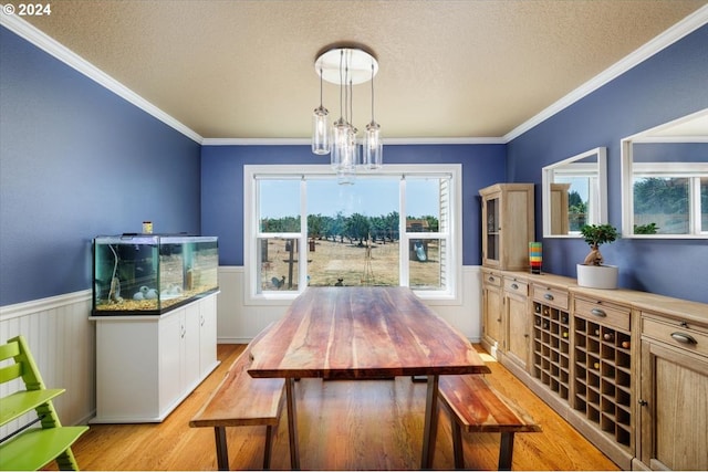 dining area featuring a chandelier, ornamental molding, a textured ceiling, and light hardwood / wood-style floors