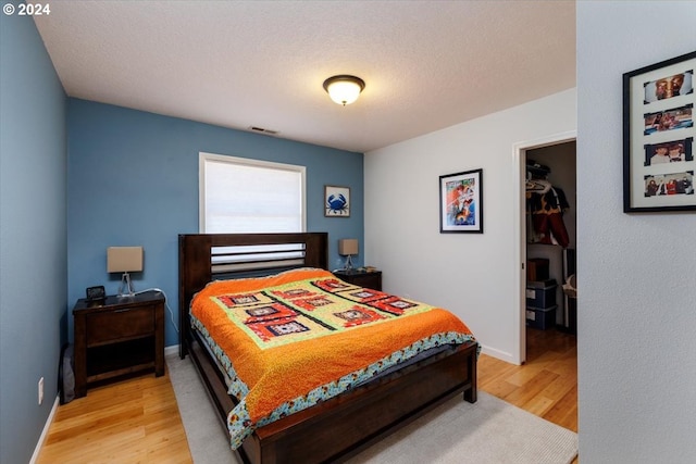 bedroom featuring a textured ceiling and light hardwood / wood-style floors