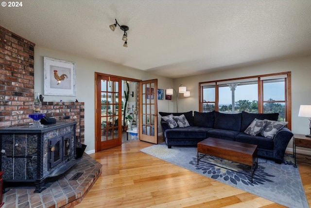 living room with french doors, wood-type flooring, a textured ceiling, and a wood stove