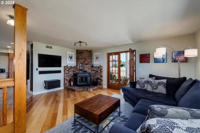 living room featuring a textured ceiling, hardwood / wood-style floors, and a wood stove