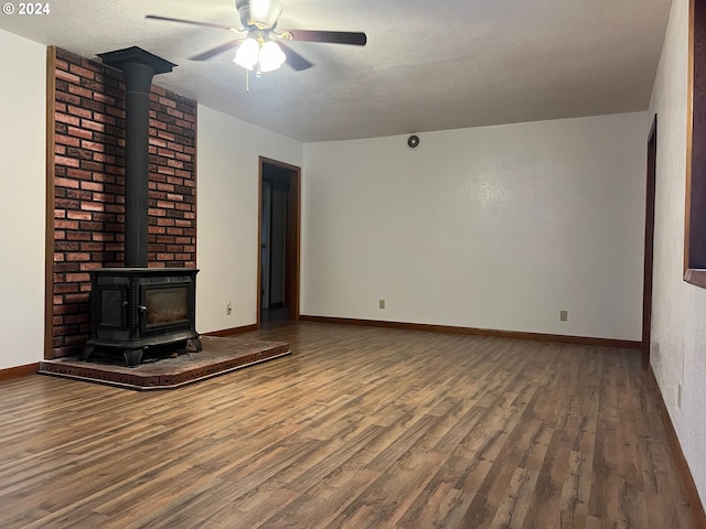 unfurnished living room featuring hardwood / wood-style flooring, ceiling fan, a textured ceiling, and a wood stove