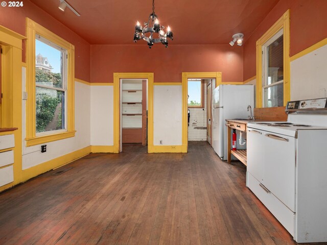 kitchen with white appliances, dark hardwood / wood-style floors, a notable chandelier, hanging light fixtures, and white cabinetry