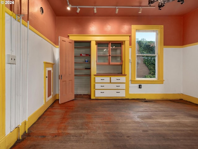 unfurnished bedroom featuring track lighting and dark hardwood / wood-style flooring