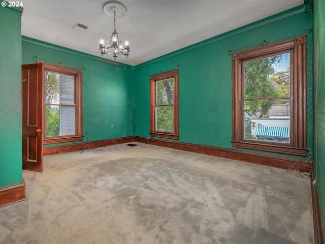 carpeted spare room with crown molding, a chandelier, and a textured ceiling