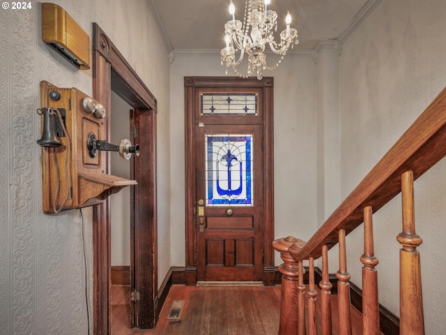 foyer entrance with ornamental molding, a chandelier, and dark hardwood / wood-style flooring