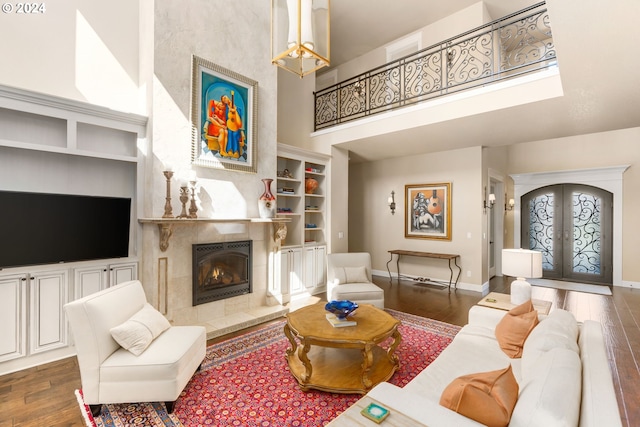 living room with a high ceiling, french doors, dark hardwood / wood-style floors, and built in features