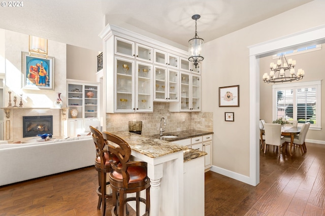 kitchen featuring pendant lighting, sink, white cabinetry, a kitchen bar, and kitchen peninsula