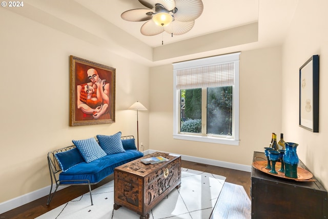 living room with hardwood / wood-style flooring, ceiling fan, and a tray ceiling