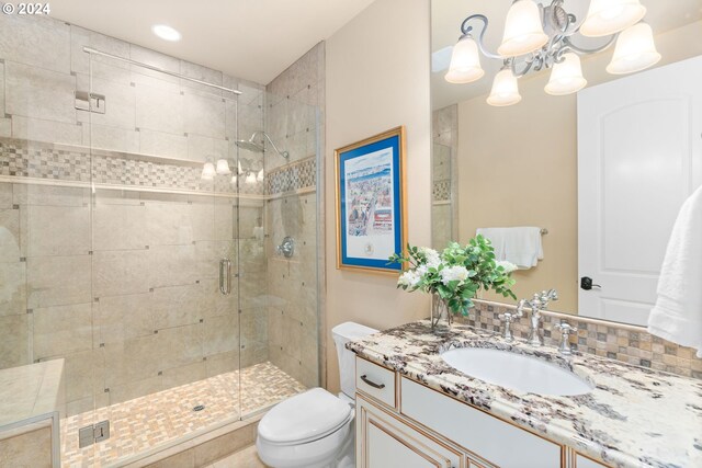 bathroom featuring vanity, backsplash, toilet, walk in shower, and a notable chandelier