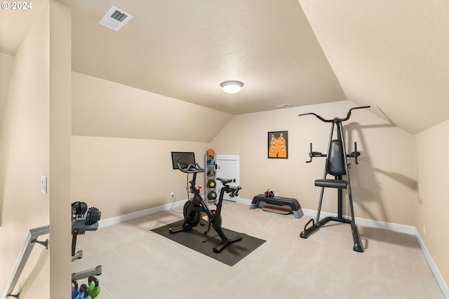 exercise room featuring carpet floors, a textured ceiling, and vaulted ceiling