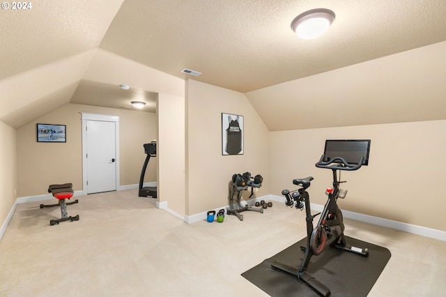 exercise room featuring a textured ceiling, carpet, and vaulted ceiling