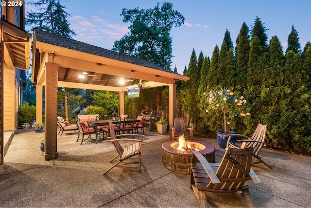 patio terrace at dusk with a gazebo, grilling area, and an outdoor fire pit