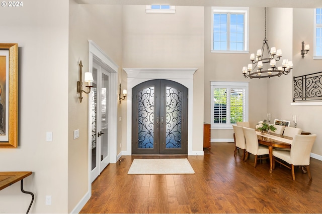 entrance foyer featuring french doors, dark wood-type flooring, and a notable chandelier