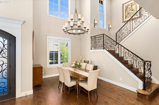 dining room featuring dark hardwood / wood-style flooring, a towering ceiling, and a notable chandelier