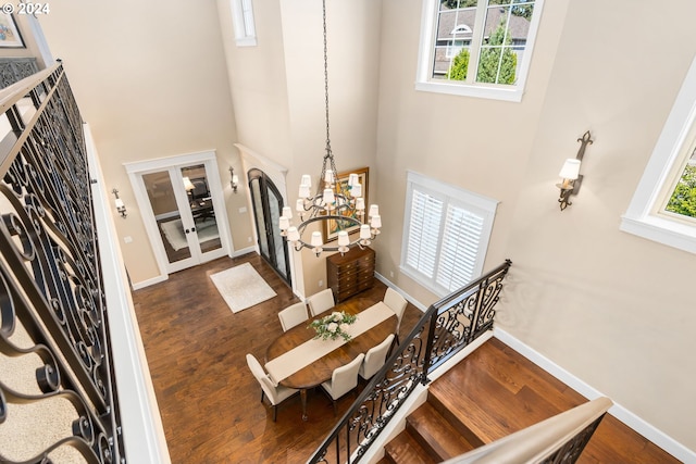 foyer entrance featuring a high ceiling, dark hardwood / wood-style floors, an inviting chandelier, and french doors