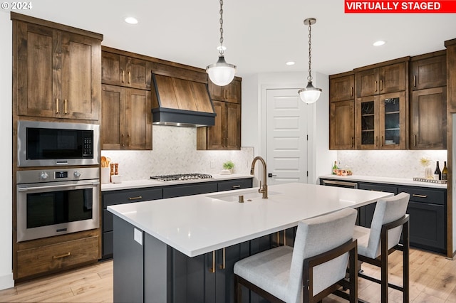 kitchen featuring stainless steel appliances, light wood-type flooring, premium range hood, and tasteful backsplash