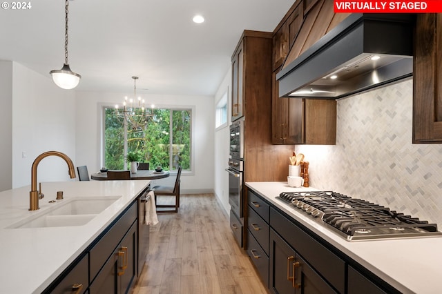 kitchen featuring appliances with stainless steel finishes, light hardwood / wood-style floors, hanging light fixtures, sink, and custom exhaust hood