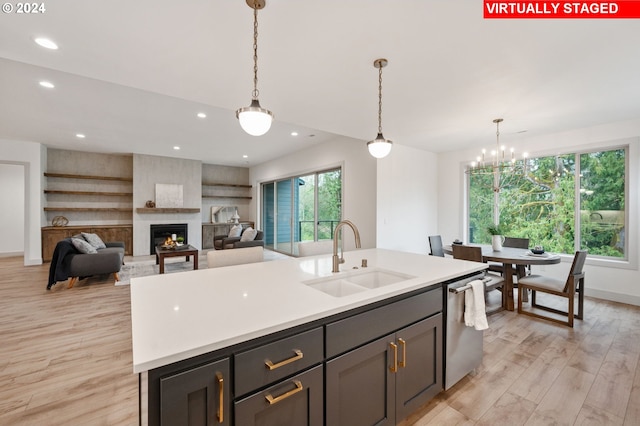 kitchen featuring light hardwood / wood-style flooring, sink, dishwasher, and a fireplace